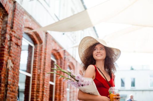 Summer sunny lifestyle portrait of young beautiful woman walking on the street market.